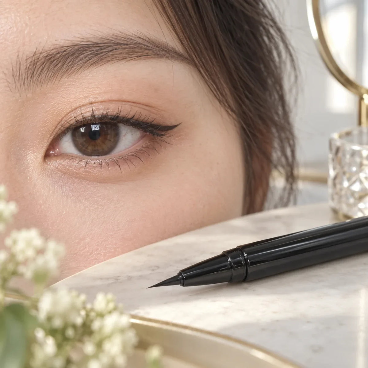 Close-up eye with a clean eyeliner line beside a slim unbranded eyeliner pen