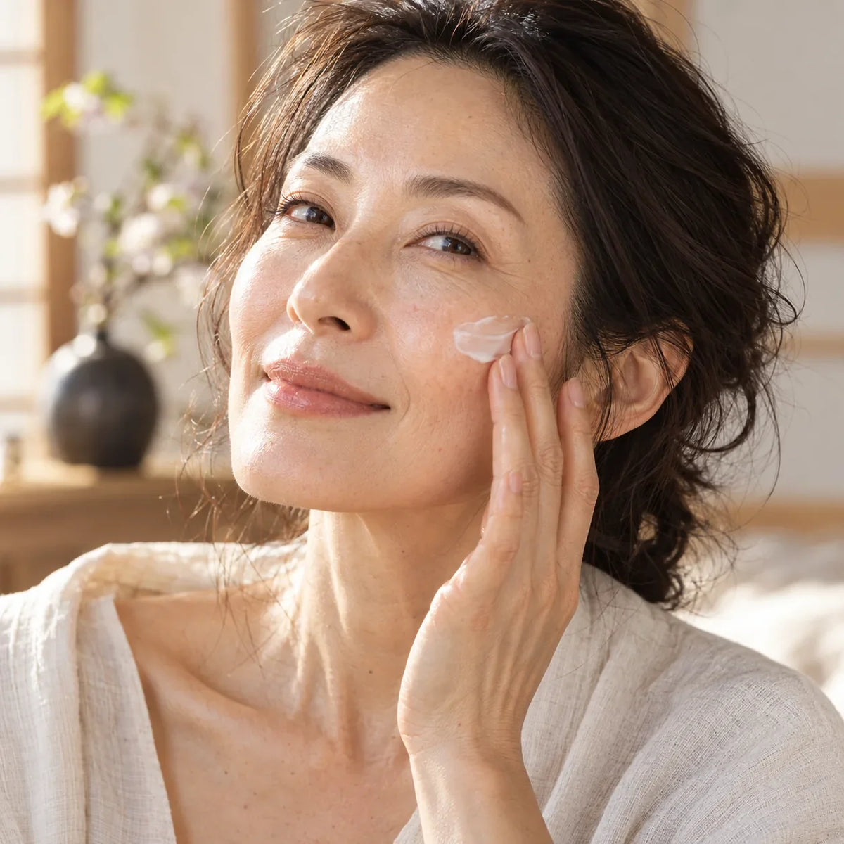 Woman in her late 40s applying moisturizer to naturally textured skin