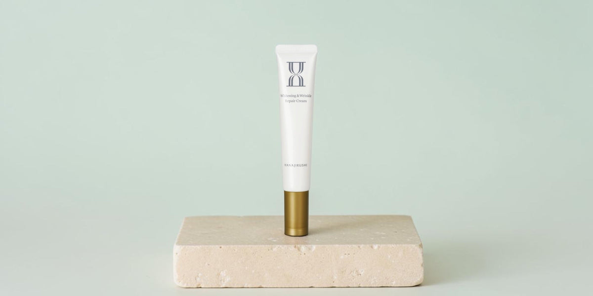 Hanajirushi skincare tube centered on an ivory pedestal against a pale aqua background